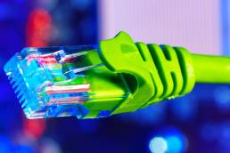 Close-up of a lime green internet cable against a blurred colourful background.